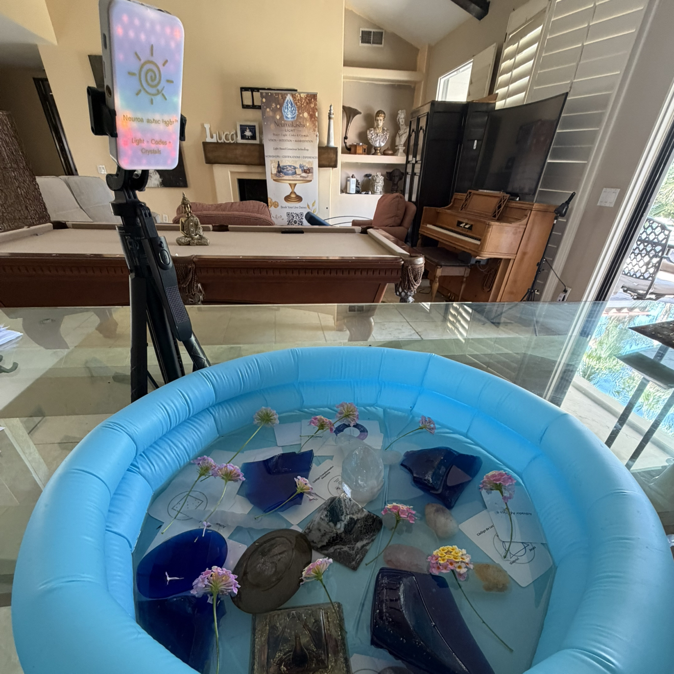 Blue inflatable pool with crystals, flowers and sacred codes for Neuroakashic Water Codes immersive therapy